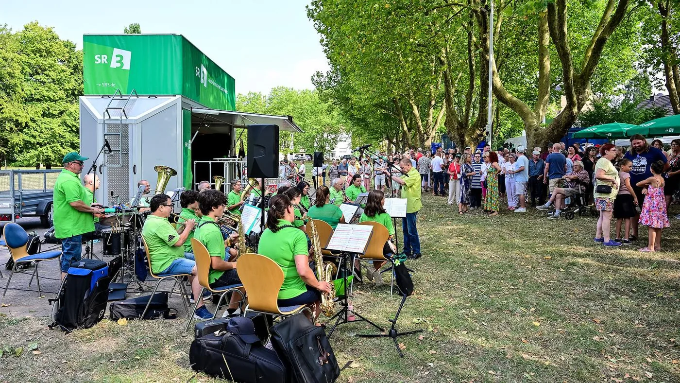 Der grüne SR-3-Ü-Wagen, ein spielender Orchesterverein und zahlreiche Gäste auf dem Veranstaltungsplatz in Hostenbach.